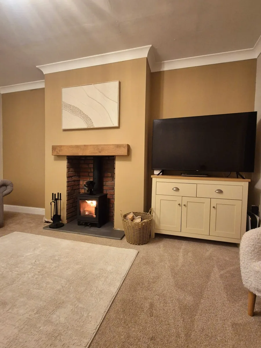 The same room finished, with a decorated chimney breast, timber mantel and wood-burning stove